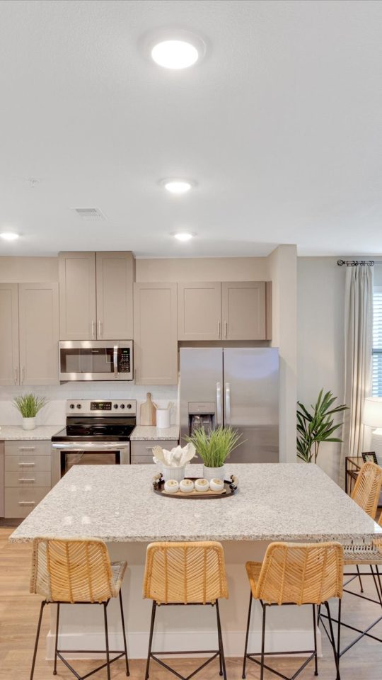 a large open kitchen and living room with white cabinets at The Town Arlington