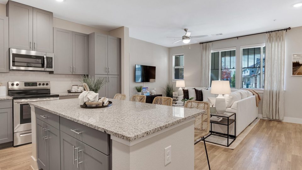 a large open kitchen with stainless steel appliances and gray cabinets at The Town Arlington